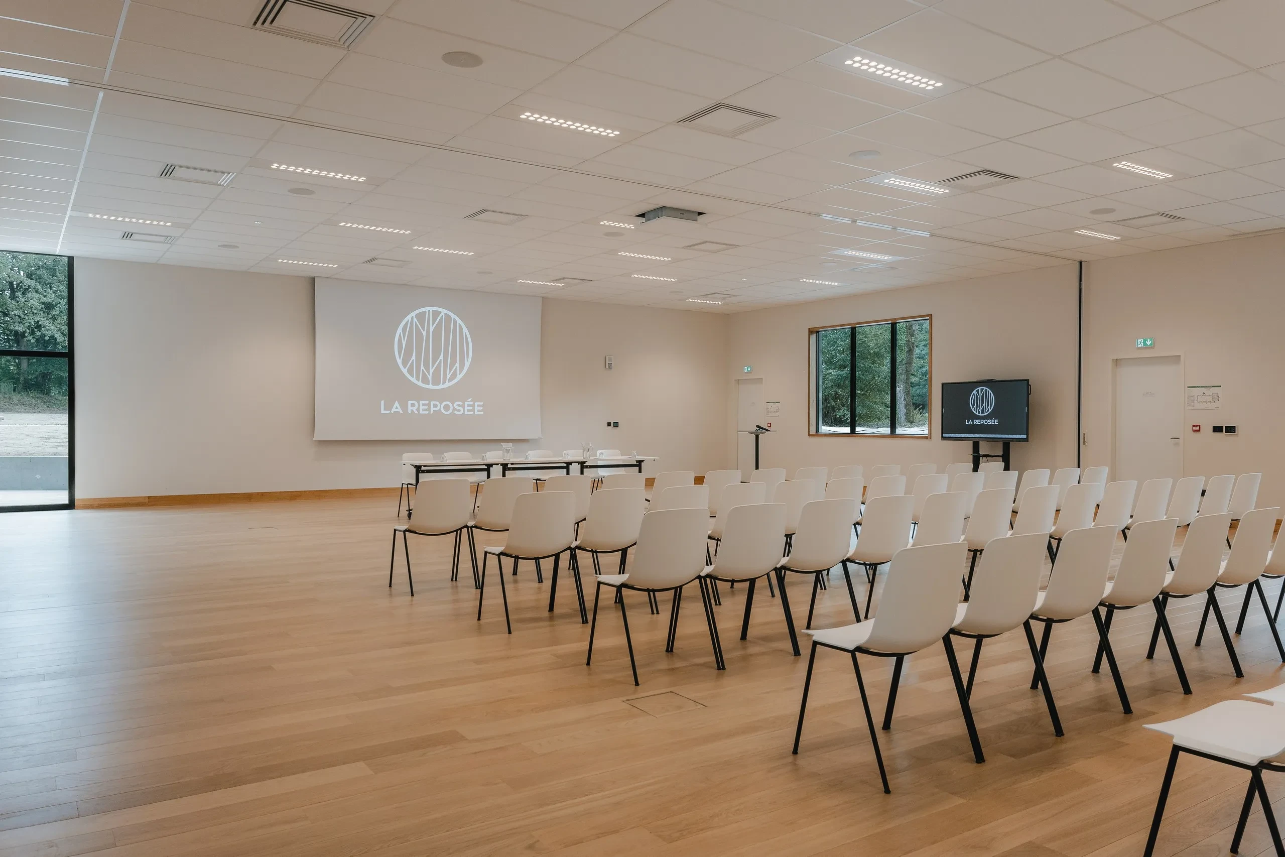 Salle de conférence vide avec rangées de chaises.